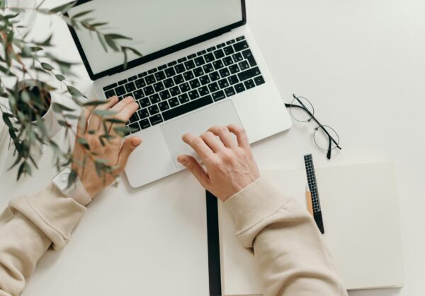 Free An overhead view of a person working on a laptop in a minimalist home office setting. Stock Photo
