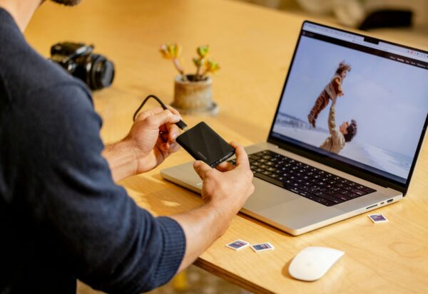 The-_Backup-Exit_-Strategy_-Can-You-Move-Your-Data-Without-the-Vendors-Help_-scaled.jpg A man sitting at a table with a laptop and cell phone