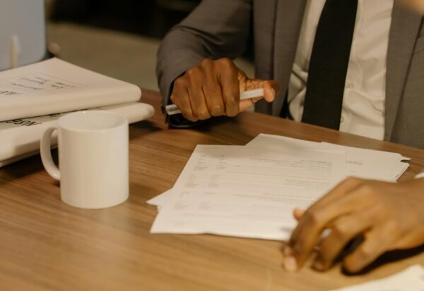 pexels-cottonbro-8369207-scaled.jpg Free Close-up of a businessman holding and reviewing documents on a wooden desk. Stock Photo