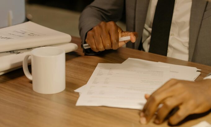 pexels-cottonbro-8369207-scaled.jpg Free Close-up of a businessman holding and reviewing documents on a wooden desk. Stock Photo