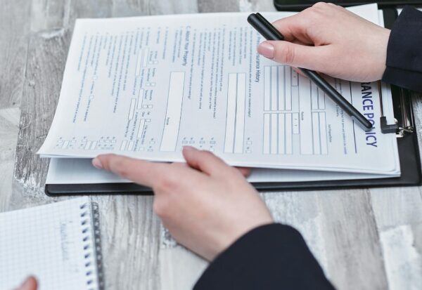 pexels-mikhail-nilov-7731326-scaled.jpg Free Close-up of hands analyzing insurance policy paperwork with pen on table. Stock Photo