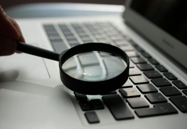 magnifying glass near gray laptop computer